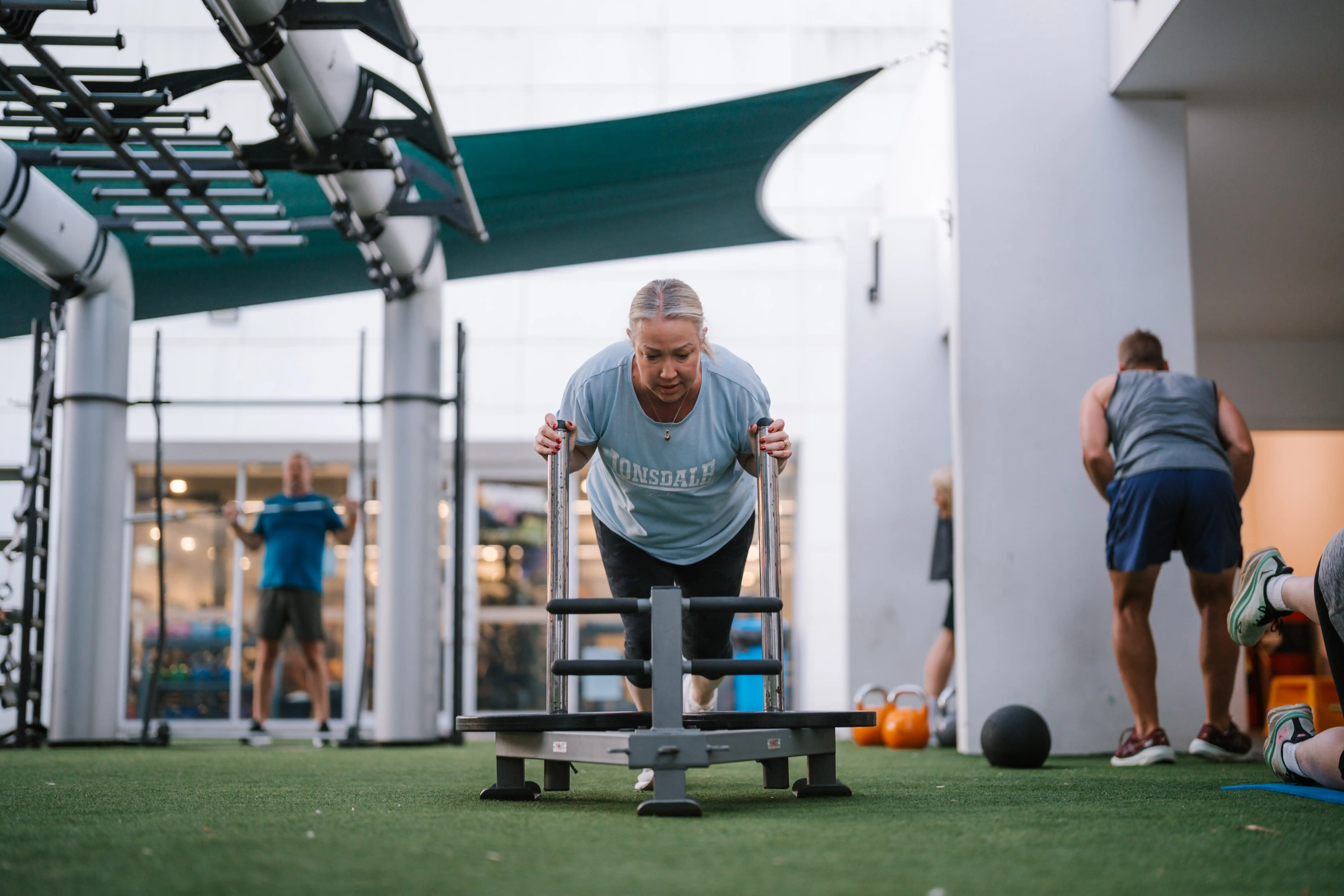Person pushing weights in gym outrace area.